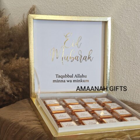 Gouden Eid Mubarak chocoladebox, open display met 16 luxe chocolates en ‘Taqabbal Allahu minna wa minkum’ op deksel.